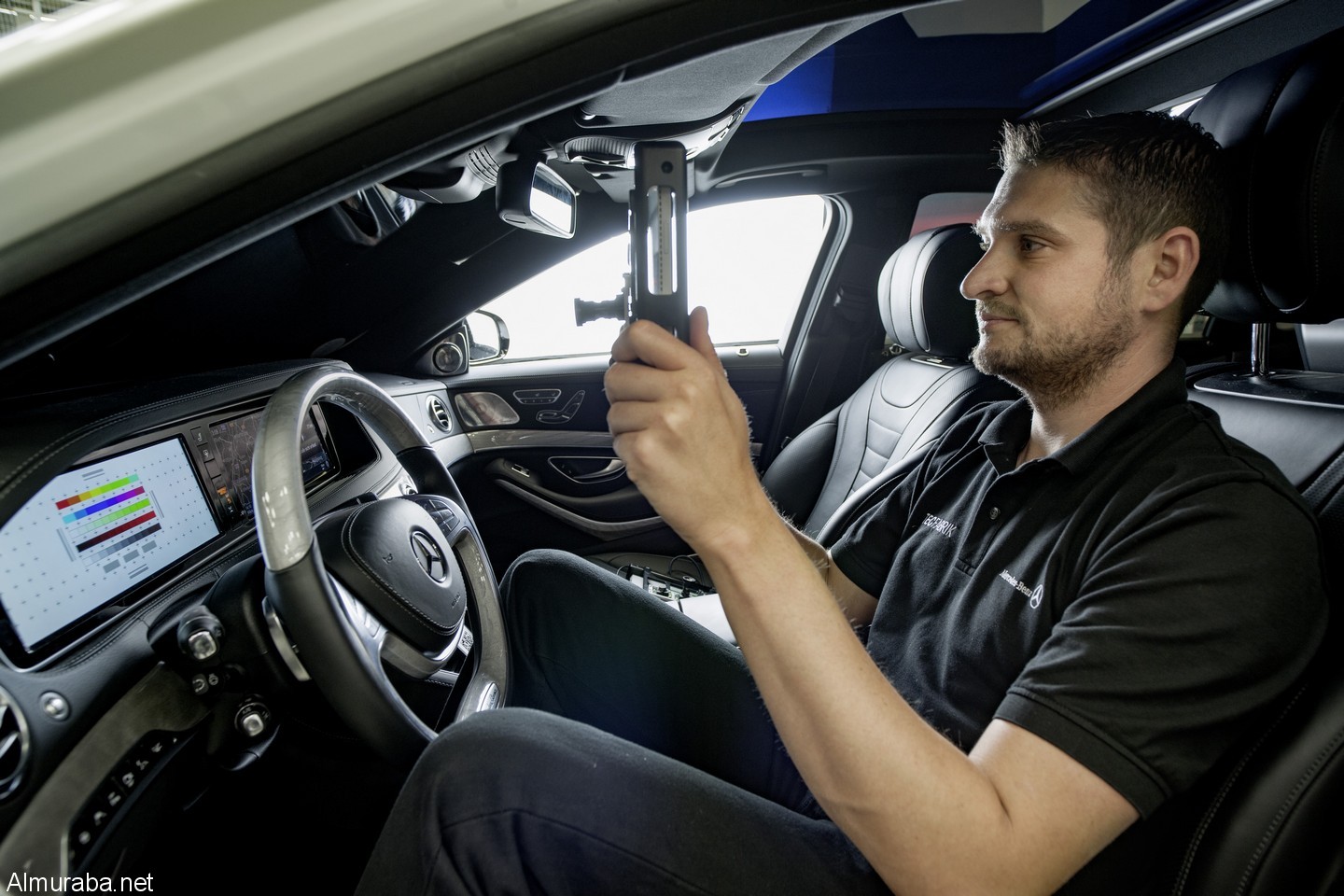 Kalibrierung von Head-up Displays (HUD) mit mobilem Endgerät: Benjamin Winkler, Verfahrensentwicklung Absicherungstechnologien, sitzt mit einem Tablet-Computer, der mit zwei zusätzlichen Kameras bestückt ist, hinter dem Lenkrad. Die eine Kamera misst das Tablet auf einen bestimmten Punkt in der Instrumententafel ein Calibration of head-up displays (HUD) with mobile devices: Benjamin Winkler, Process Engineer, sits behind the wheel with a tablet computer equipped with two additional cameras. One camera calibrates the tablet's position to a certain point in the dashboard