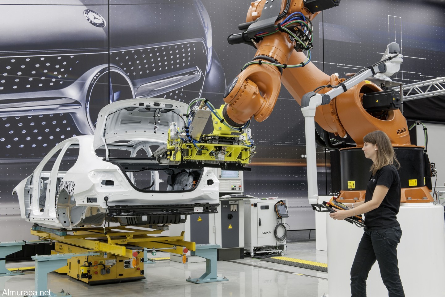 Lissy Brückner, Verfahrensentwicklung Montagetechnik und Modularisierung, beim Einbau der Batterie in ein Hybridfahrzeug. Kein Zaun trennt den Menschen mehr vom Kooperationspartner Roboter Lissy Brückner, Process Engineer, installing the battery into a hybrid vehicle. No fence separates the human operator from her cooperating robot